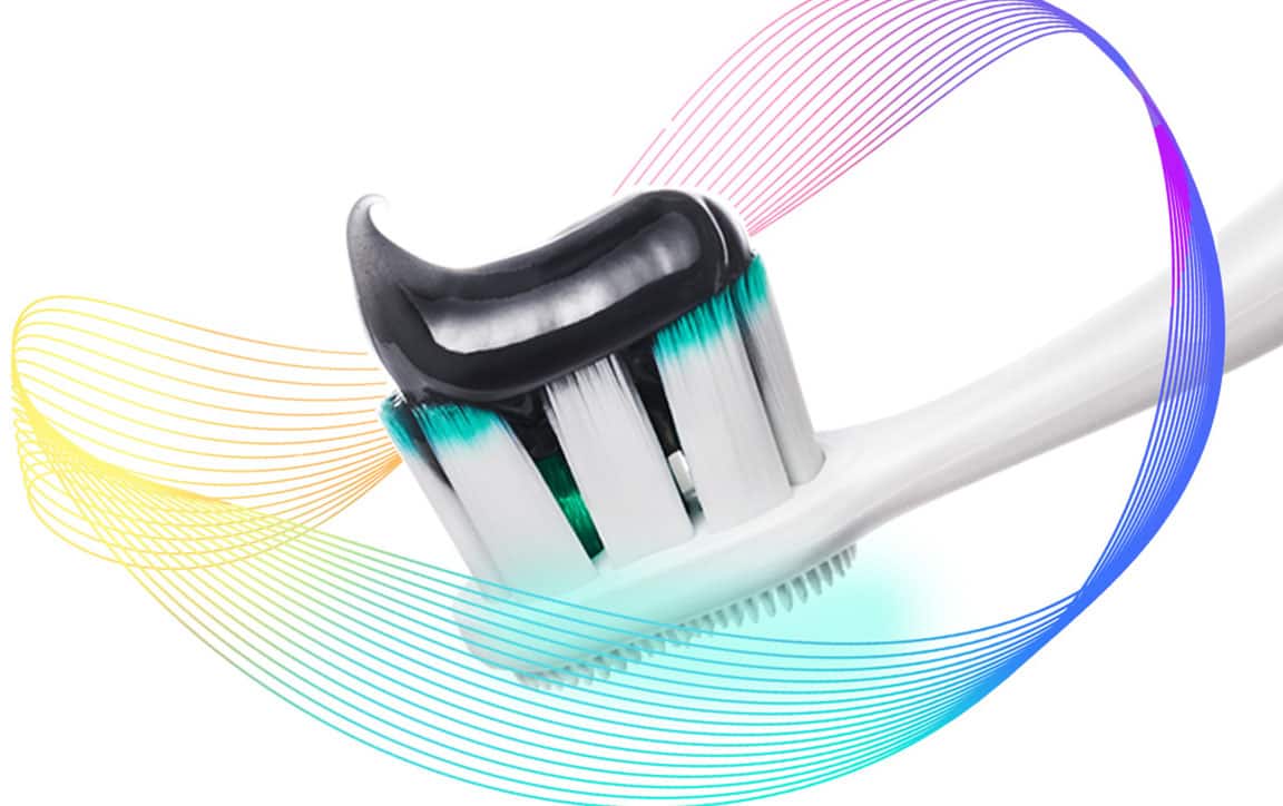 Berus gigi Colgate Total dengan ubat gigi di atas kepala berus, dikelilingi oleh sinaran pencegahan berwarna-warni