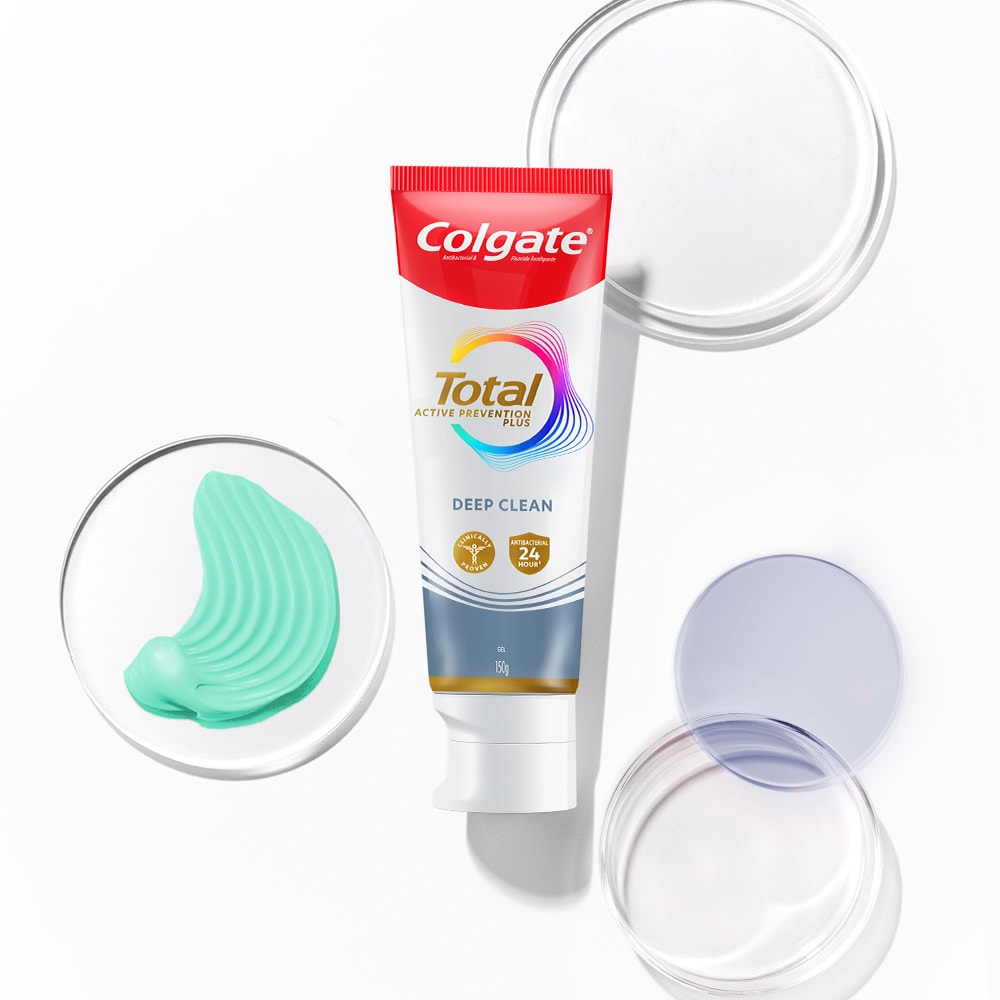 Tiub ubat gigi Colgate Total di latar depan, dengan buih lutsinar dan spektrum di latar belakang