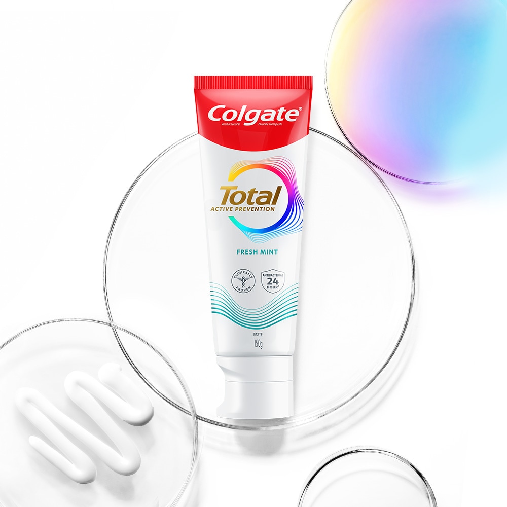 Tiub ubat gigi Colgate Total di latar depan, dengan buih lutsinar dan spektrum di latar belakang