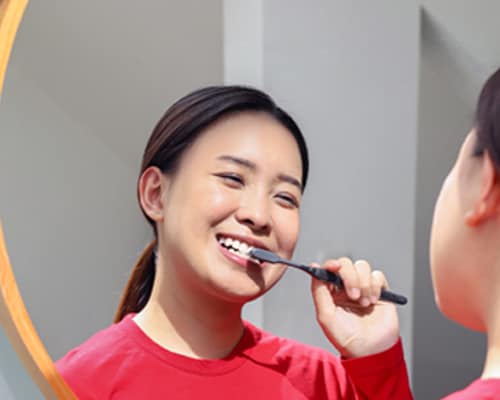 Wanita Asia memberus gigi dengan Berus Gigi Colgate SlimSoft Charcoal
