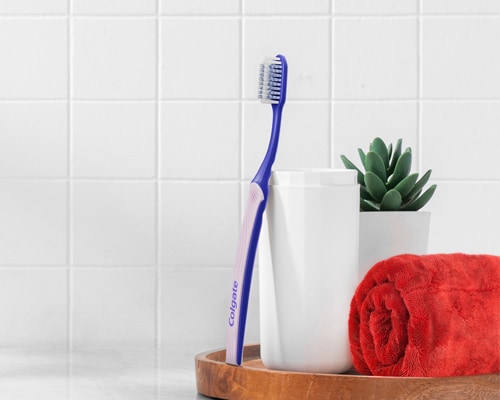 Berus Gigi Colgate SlimSoft Ortho bersandar pada cawan
